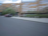 a blurry photo of a man skateboarding on a city street with buildings in the background