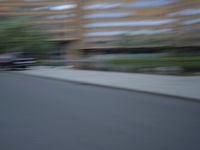 a blurry photo of a man skateboarding on a city street with buildings in the background