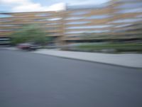 a blurry photo of a man skateboarding on a city street with buildings in the background