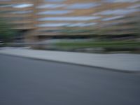 a blurry photo of a man skateboarding on a city street with buildings in the background