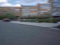 a blurry photo of a man skateboarding on a city street with buildings in the background