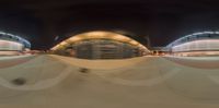 a blurry image of a skateboarder in the night with lights on, at a skate park