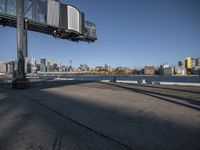 a lone skateboarder in a large city setting on a large concrete road under a bridge