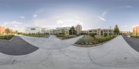 a skateboarder rides his board in the cement near a city park and buildings