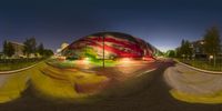 the skateboarder rides through the colorful paint covered ramp in the night time in the park