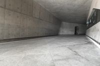 a skateboarder skating down a concrete alley way and its reflection on the wall