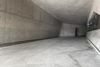 a skateboarder skating down a concrete alley way and its reflection on the wall