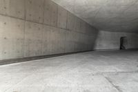 a skateboarder skating down a concrete alley way and its reflection on the wall