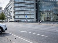 a man on a skateboard crosses an empty street past large buildings and tall office towers