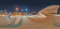 a skateboarder riding along a concrete surface at night time on his skate board