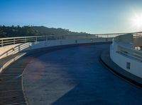 a skateboarder doing tricks in an empty track with a sky background as the sun rises