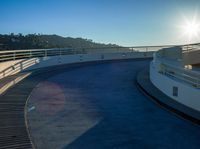 a skateboarder doing tricks in an empty track with a sky background as the sun rises