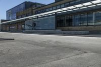 a skateboarder on the street in front of a building in an empty lot