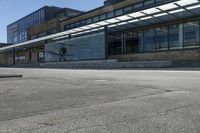 a skateboarder on the street in front of a building in an empty lot