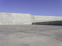 a skateboarder grinding his board outside on concrete blocks with blue sky above the wall