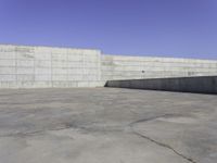 a skateboarder grinding his board outside on concrete blocks with blue sky above the wall