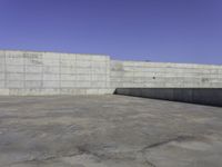 a skateboarder grinding his board outside on concrete blocks with blue sky above the wall