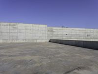 a skateboarder grinding his board outside on concrete blocks with blue sky above the wall