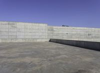 a skateboarder grinding his board outside on concrete blocks with blue sky above the wall