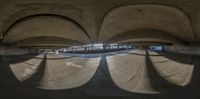 a skate boarder grinds his board in a curved room with arches overhead the photo