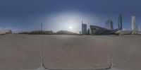 a skateboarder in the air after riding a ramp outside of buildings with a city view of the sun in the background