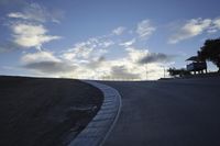 a lone skateboarder riding a bike on a hilly road in the sun with grass and trees