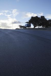 a lone skateboarder riding a bike on a hilly road in the sun with grass and trees