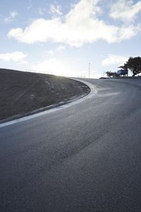 a lone skateboarder riding a bike on a hilly road in the sun with grass and trees