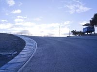 a lone skateboarder riding a bike on a hilly road in the sun with grass and trees