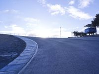 a lone skateboarder riding a bike on a hilly road in the sun with grass and trees