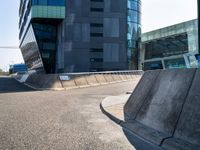 the skate boarder is skating outside of the building near a curbed area that is empty