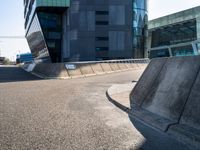 the skate boarder is skating outside of the building near a curbed area that is empty