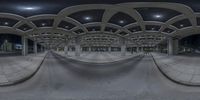 a skateboarder performs tricks in an indoor area of concrete and arches, with an overhead perspective view