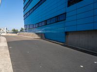 a skateboarder is riding down a ramp in an industrial building setting in front of a blue - clad building