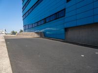 a skateboarder is riding down a ramp in an industrial building setting in front of a blue - clad building