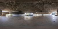 a skateboarder riding underneath a very long ceilinged building with curved walls in the background