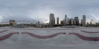 skateboarder performing trick at skate park with city skyline in background and cloudy sky