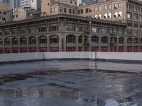 the skateboarder stands on a frozen skating rink in the city as the sun sets