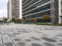 a person is riding a skateboard on the cement outside of a building that has many windows