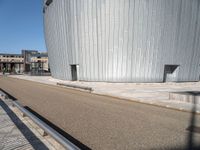 a man riding his skateboard across a parking area near a building by the sea