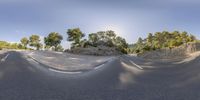 a skateboarder riding up a mountain near a rocky terrain with trees on both sides and rocks in the distance