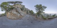 a skateboarder performs a trick down a mountain side road on his board in a fisheye lens