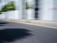 the skateboarder is going down the road in the blurry photo, which appears to be in motion