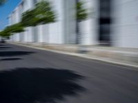 the skateboarder is going down the road in the blurry photo, which appears to be in motion