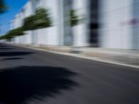 the skateboarder is going down the road in the blurry photo, which appears to be in motion