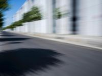 the skateboarder is going down the road in the blurry photo, which appears to be in motion