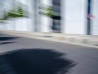 the skateboarder is going down the road in the blurry photo, which appears to be in motion
