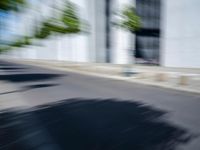 the skateboarder is going down the road in the blurry photo, which appears to be in motion