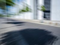 the skateboarder is going down the road in the blurry photo, which appears to be in motion