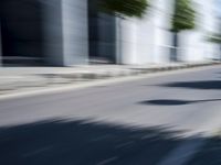 the skateboarder is going down the road in the blurry photo, which appears to be in motion